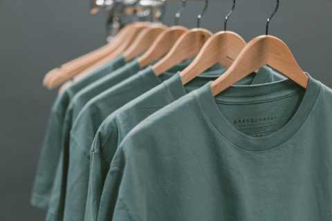 Green shirts hanging on wooden hangers.